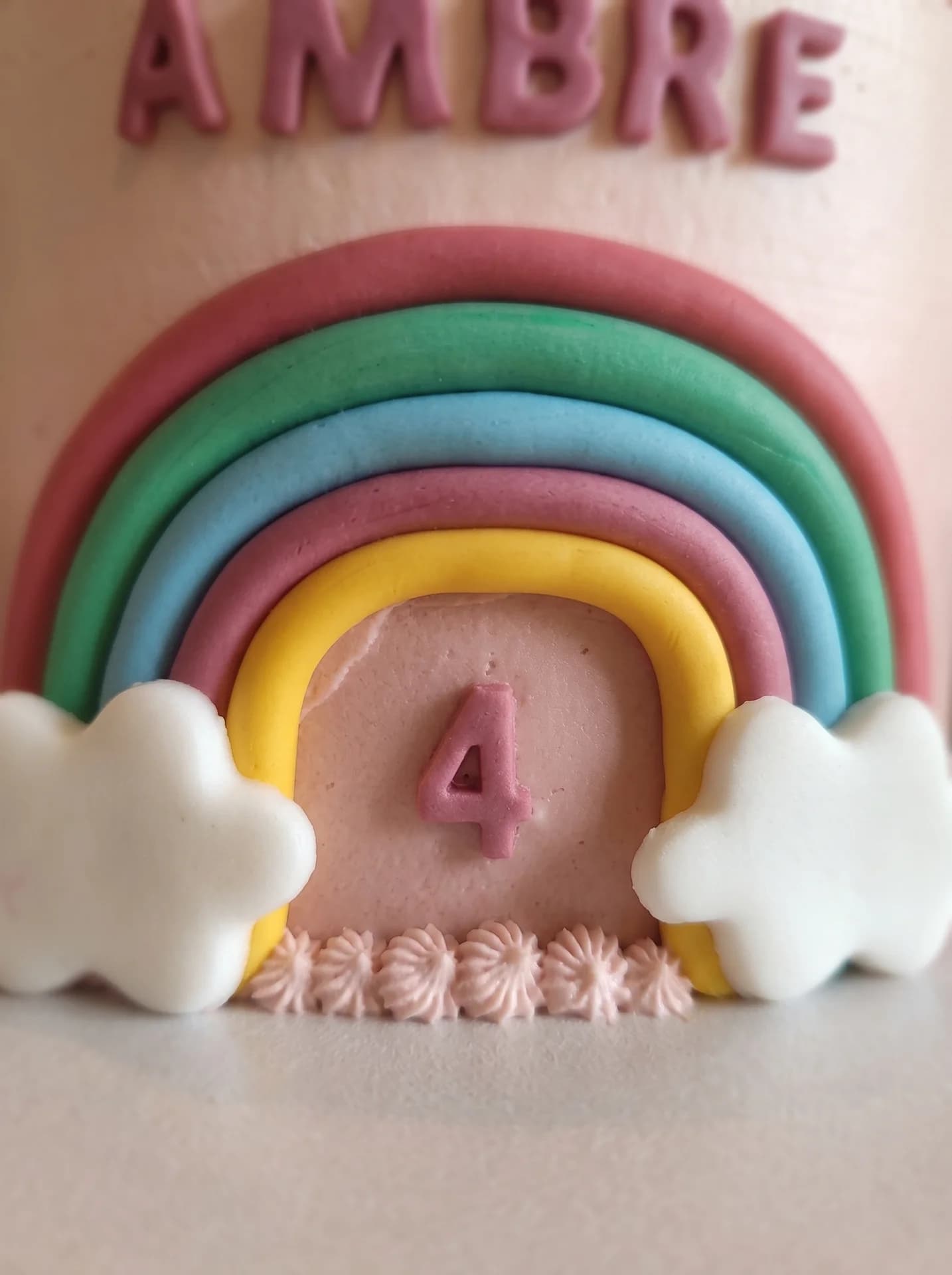 Arc-en-ciel en pâte à sucre, nuages blancs et chiffre quatre rose
